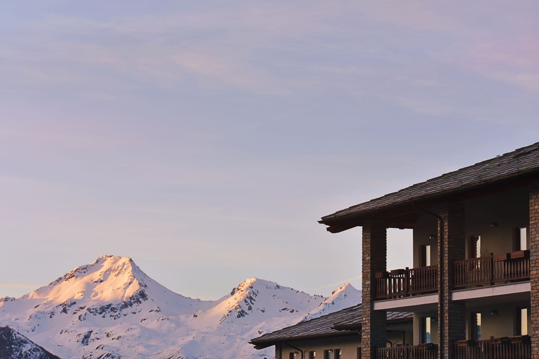 Résidence de station et sommets enneigés au coucher du soleil