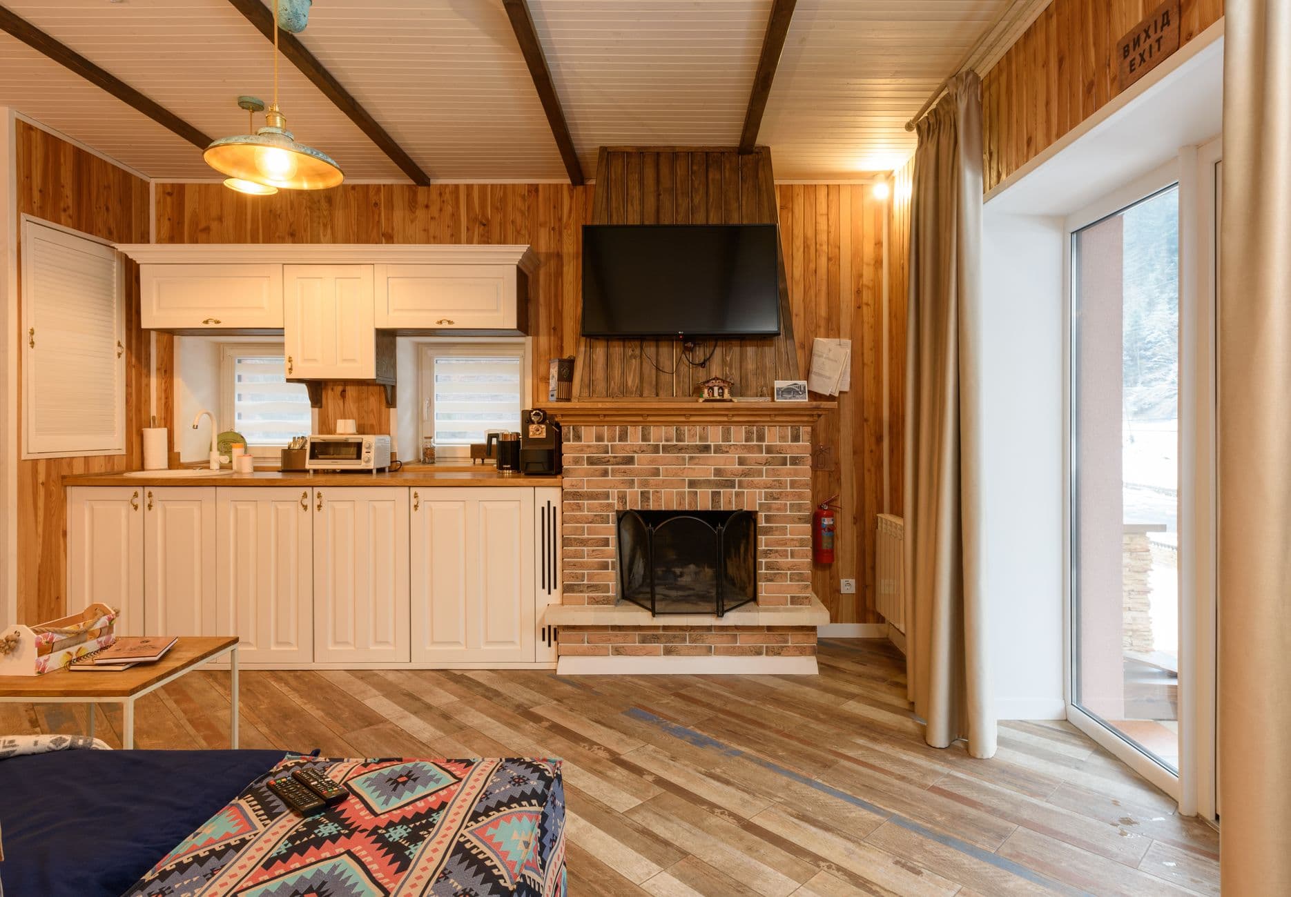 Séjour d'un chalet avec cheminée, cuisine équipée et baie vitrée sur la neige