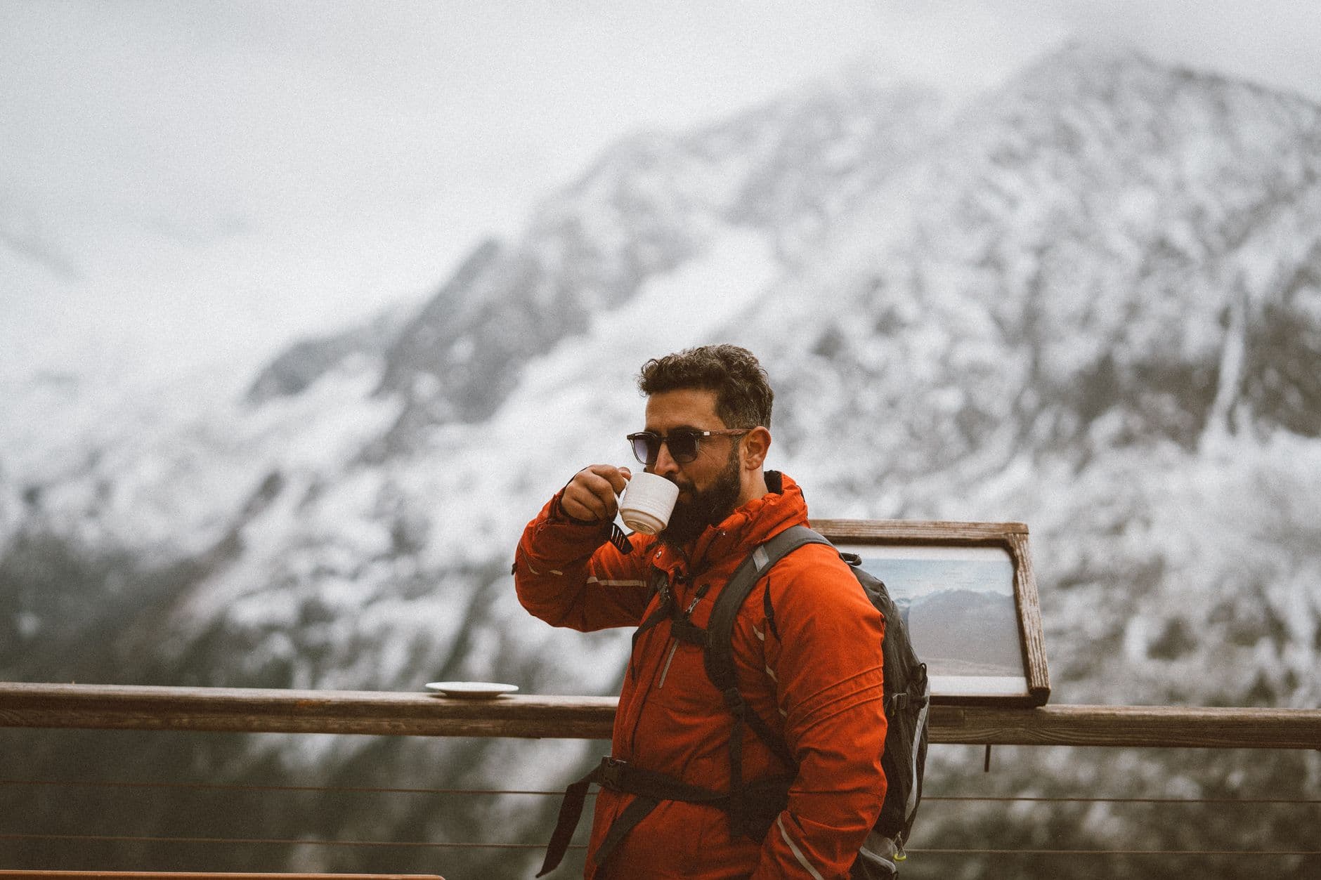 Un voyageur boit un café face aux sommets enneigés