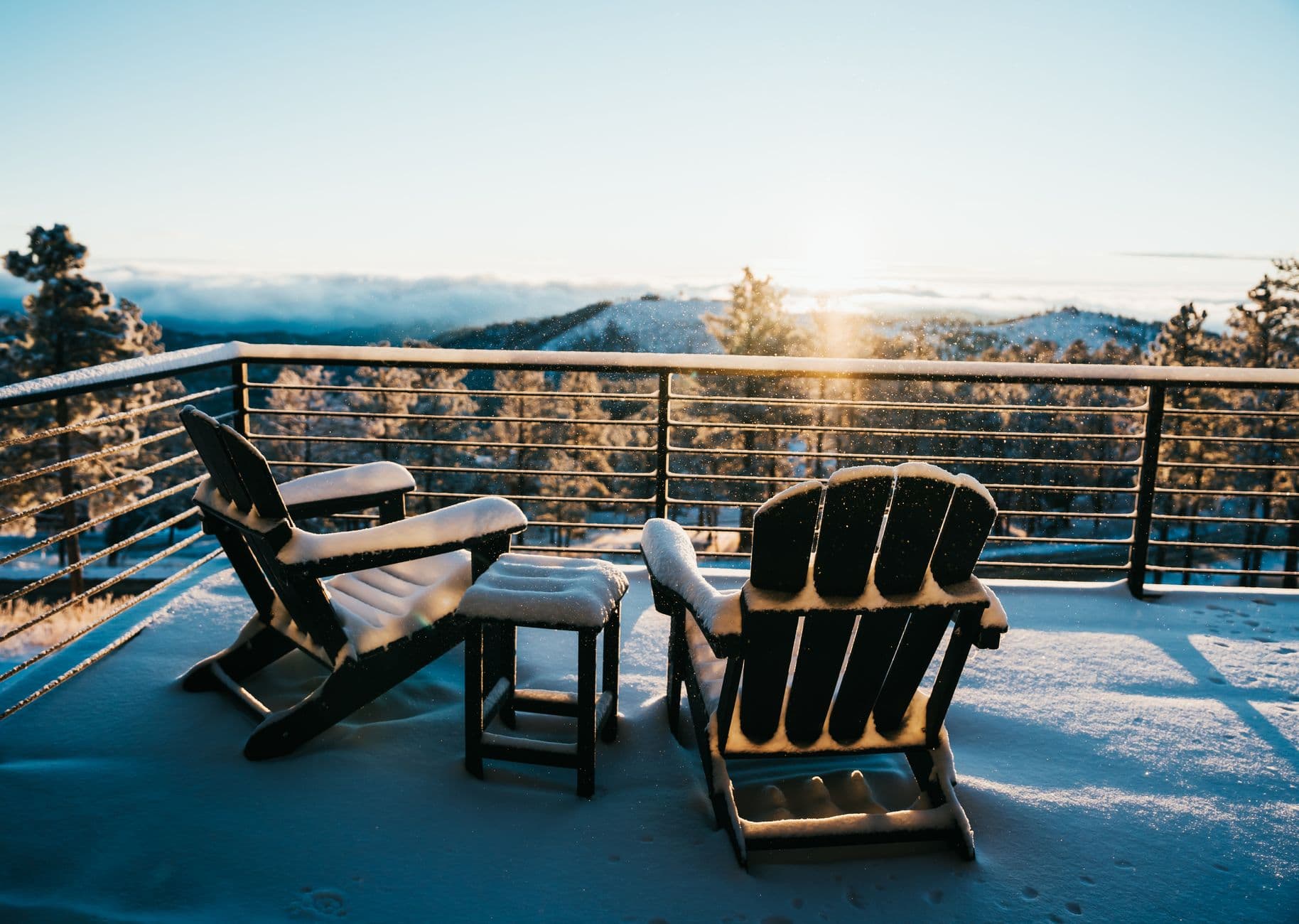 Deux fauteuils sous la neige sur une terrasse de montagne, au lever du soleil