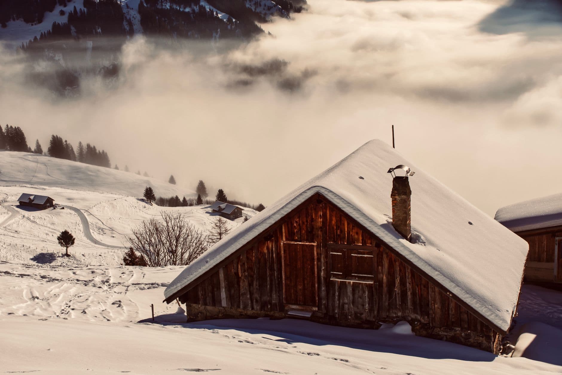 Chalet de bois isolé au-dessus d'une mer de nuages, en hiver